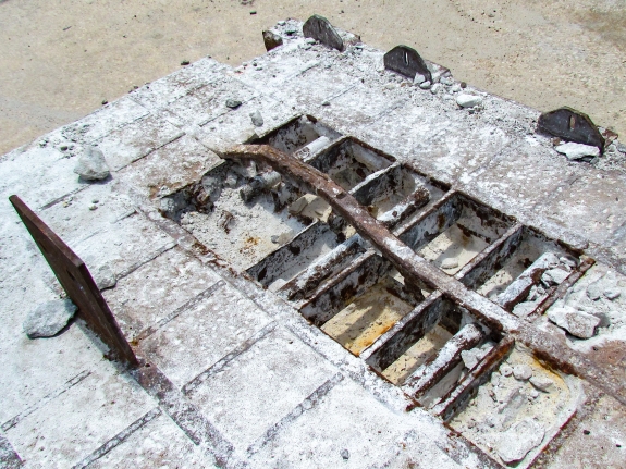 Large-format photograph: Close-up view of a removed Crawlerway Grid Panel, showing Top Chord construction (and corrosion damage) in area where concrete fill has been chipped out of the Panel. Photo credit: Withheld by request.